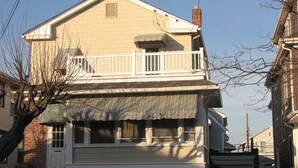 Ein zweigeschossiges Haus mit Veranda, überdachter Eingangspforte und sichtbarem Anbau für eine Garage.
