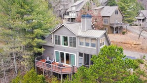 Ein zweistöckiges Haus mit Balkon, umgeben von Bäumen.