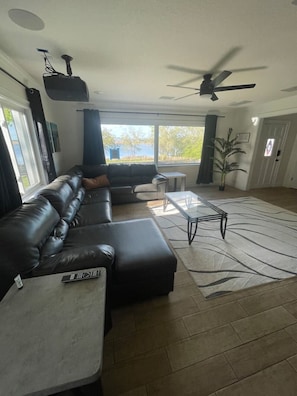 A living room with a sectional sofa, a coffee table, and a ceiling fan. - Lakefront Pool Retreat • Theater 7.1 • Fishing (Lake Wales)