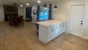 A spacious kitchen with a central island, wooden flooring, and pendant lighting.