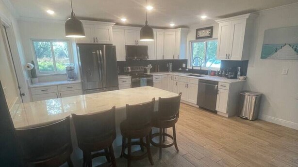 A modern kitchen with a central island, pendant lighting, and a view of the outdoors.