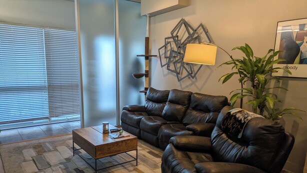 A living room with a sectional sofa, a coffee table, a lamp, and a plant. - Cozy 1-bedroom condo in serene Kansas City with AC and gym (Kansas City)