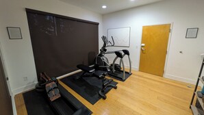 A gym with treadmills, a stationary bike, and a bench press. - Cozy 1-bedroom condo in serene Kansas City with AC and gym (Kansas City)
