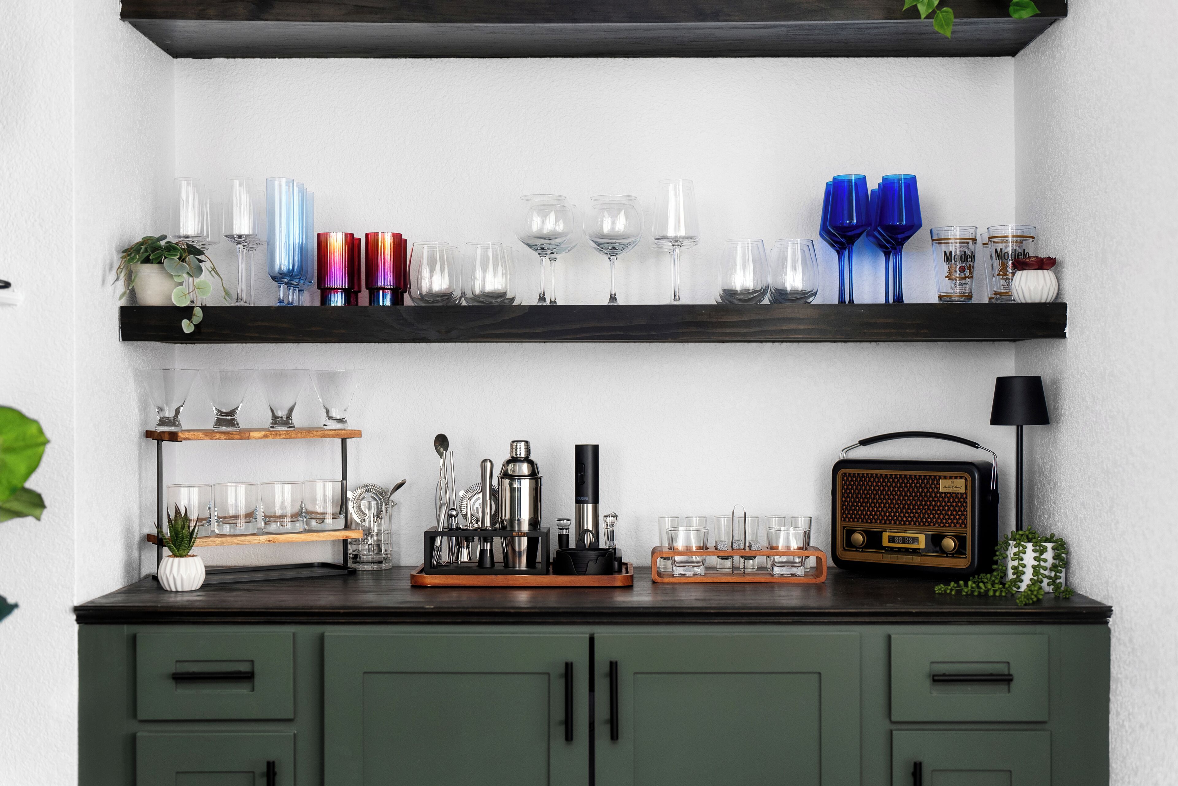 A kitchen counter with shelves holding glasses and a radio.