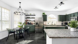 A modern kitchen with a central island, dark cabinetry, and a chandelier. - Geyser Ave (Pflugerville)