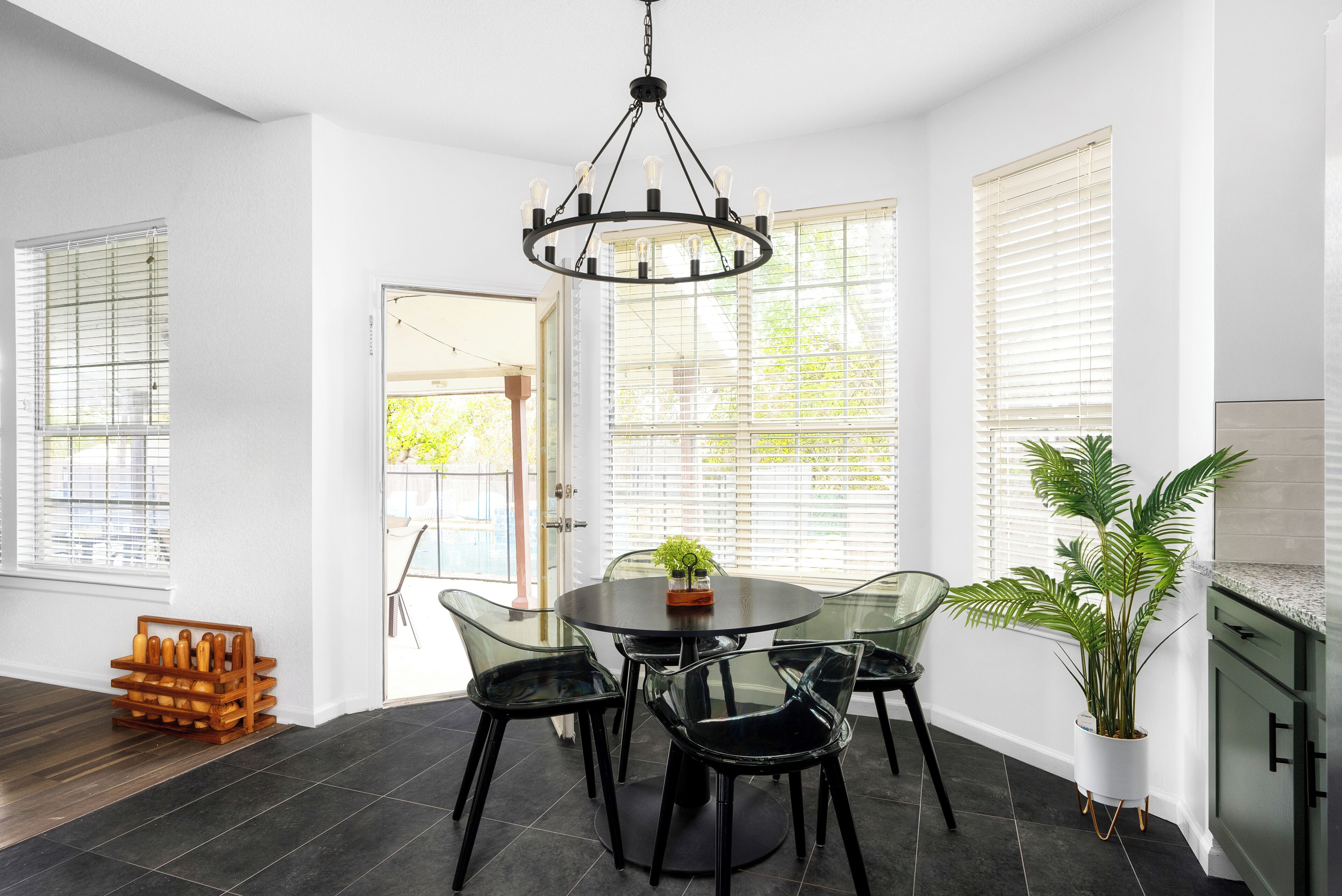 Un coin repas avec une table ronde, des chaises, un lustre et une plante en pot.