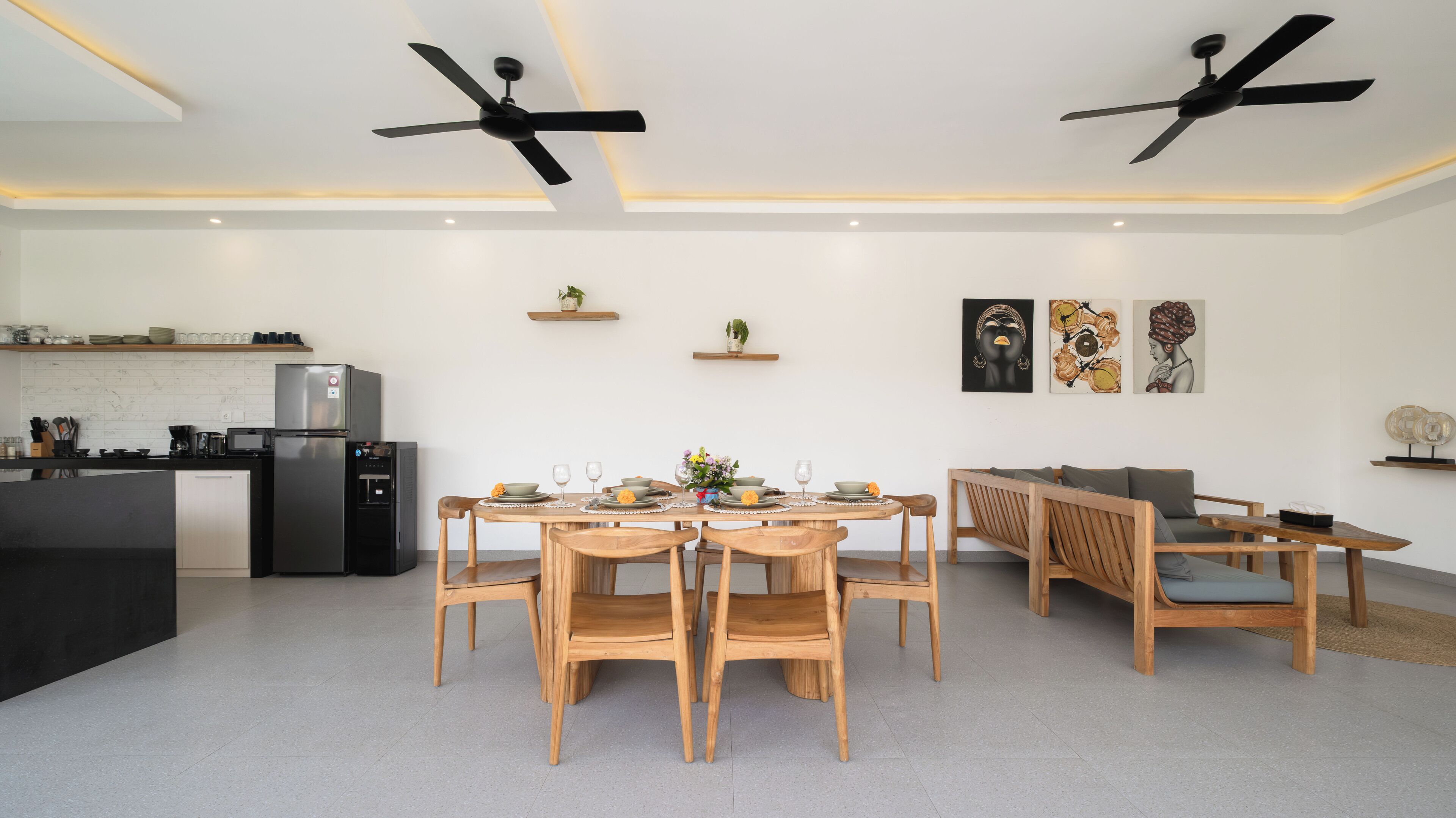 Una cocina moderna con refrigerador, microondas y cafetera. Hay una mesa de comedor con sillas y un sofá.