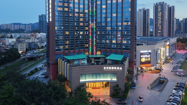 A high-rise hotel with multiple floors, a prominent entrance, and a parking area. - ShenZhen Romanjoy International Hotel (Shenzhen)