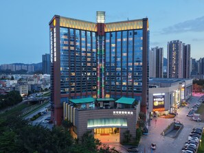 Ein Hochhaus-Hotel mit mehreren Etagen, einem markanten Eingang und einem Parkplatz.