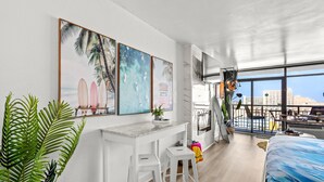 A modern hotel room with a large window, a balcony, and a beach-themed artwork on the wall. - Landmark Resort Ocean View | Beach, Pools, Lazy River (Myrtle Beach)