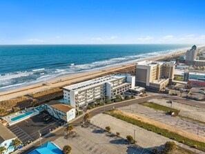 An aerial view of a coastal hotel with a pool, parking, and beachfront access. - Boardwalk Breeze, Oceanfront, Pool! Villa (Carolina Beach)