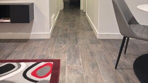 Un couloir avec un téléviseur, une chaise et un tapis à motifs.