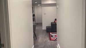 Un couloir étroit doté d’un plancher en bois, de murs blancs et d’un éclairage encastré.