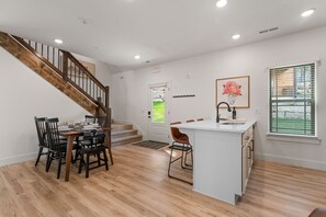 Une cuisine moderne dotée d’un îlot central, de planchers en bois et d’un escalier menant à un niveau supérieur.