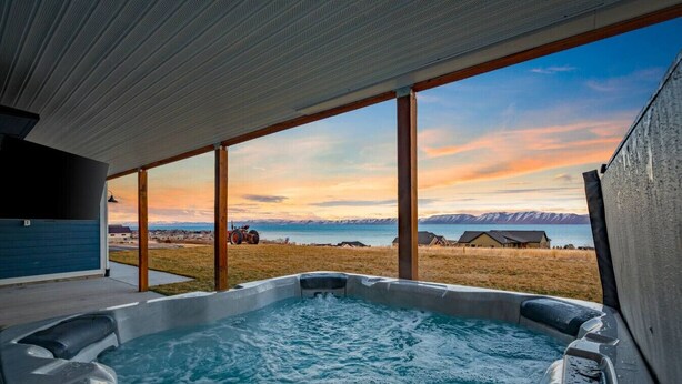 A hot tub with a view of mountains and a tractor in the background.