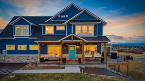 A two-story house with a porch, a front door, and a small deck.