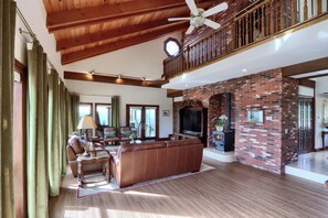A spacious living room with a large brown leather sofa, a fireplace, and a wooden ceiling. - NEW! Luxury Yosemite Estate-Pool-Hot Tub- 5BR 4.5BA-Sleeps 16-55 Private Acres. (Oakhurst)
