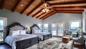 Une chambre avec deux lits, un ventilateur de plafond et une vue sur l’extérieur, accessible par une porte coulissante.