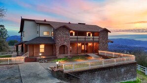Une maison à deux étages avec une façade en pierre, un balcon et une vue sur le paysage.