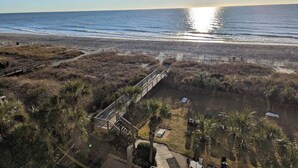 A coastal landscape with a wooden boardwalk leading to a beach, surrounded by vegetation and a clear sky. - Beachfront Paradise - Stunning views - Stargazzing (Myrtle Beach)