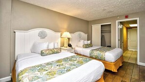 A hotel room with two beds, a nightstand with a lamp, a decorative wall piece, and a door leading to another room. - Beachfront Paradise - Stunning views - Stargazzing (Myrtle Beach)