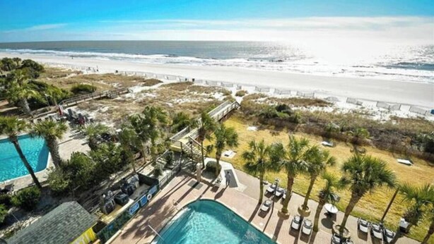 A resort with a swimming pool, beach view, and palm trees. - Beachfront Paradise - Stunning views - Stargazzing (Myrtle Beach)