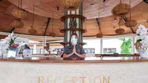 A reception desk with a clock, a sign reading 'RECEPTION,' and a person standing behind it.