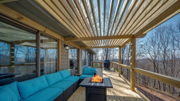 An outdoor deck with a fire feature, a blue sofa, and a pergola. - Scenic Solitude in Lake Lure (Lake Lure)
