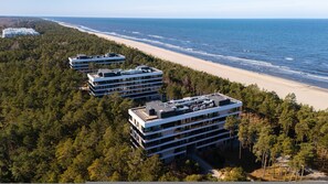 Ein Küstenhotelkomplex mit mehreren Gebäuden, umgeben von dichtem Wald und Blick auf Strand und Meer.