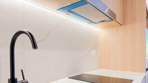 Una cocina moderna con un grifo negro, un lavamanos de acero inoxidable y una encimera de madera.