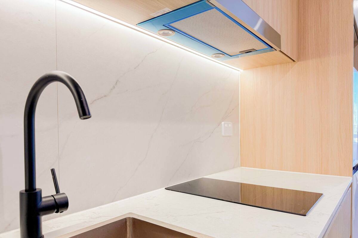 A modern kitchen with a black faucet, a stainless steel sink, and a wooden countertop.