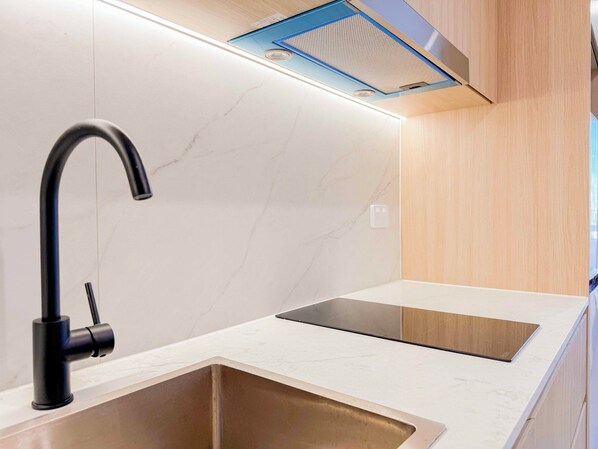 A modern kitchen with a black faucet, a stainless steel sink, and a wooden countertop. - Auburn Studio (Auburn)