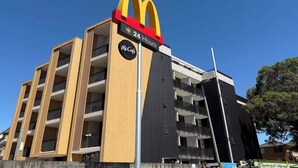 Un restaurante McDonald's con diseño moderno, que incluye un logotipo destacado y un letrero que indica servicio las 24 horas.