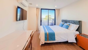Habitación de hotel con cama, televisión, aire acondicionado, ventana con cortinas y vistas al exterior.