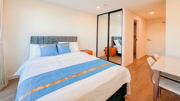 Una habitación de hotel con cama, escritorio, silla y espejo.