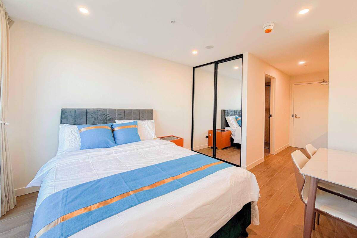 A hotel room with a bed, a desk, a chair, and a mirror.