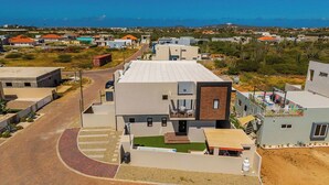 A modern building with a flat roof, a small front yard, and a street view. - NEW 4BR3.5BA Home w/Private Pool ~ Good Location (Noord)