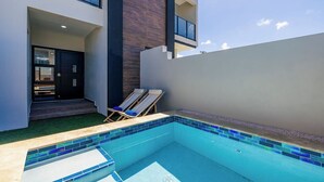 A modern building with a swimming pool, a door, and two lounge chairs. - NEW 4BR3.5BA Home w/Private Pool ~ Good Location (Noord)