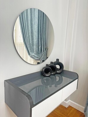 A modern bathroom vanity with a glass top, a round mirror, and a towel rack. - Two-bedroom apartment in Qasr El Nil district overlooking the Nile River (cairo -downtowwn -Qasr El-Nil District)