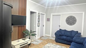 Ein Wohnzimmer mit Sofa, Fernseher, Schrank und einer Tür mit Wanddeko.