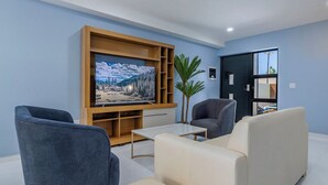Un salon moderne doté d’un téléviseur à écran plat, de deux canapés, d’une table basse et d’une bibliothèque.