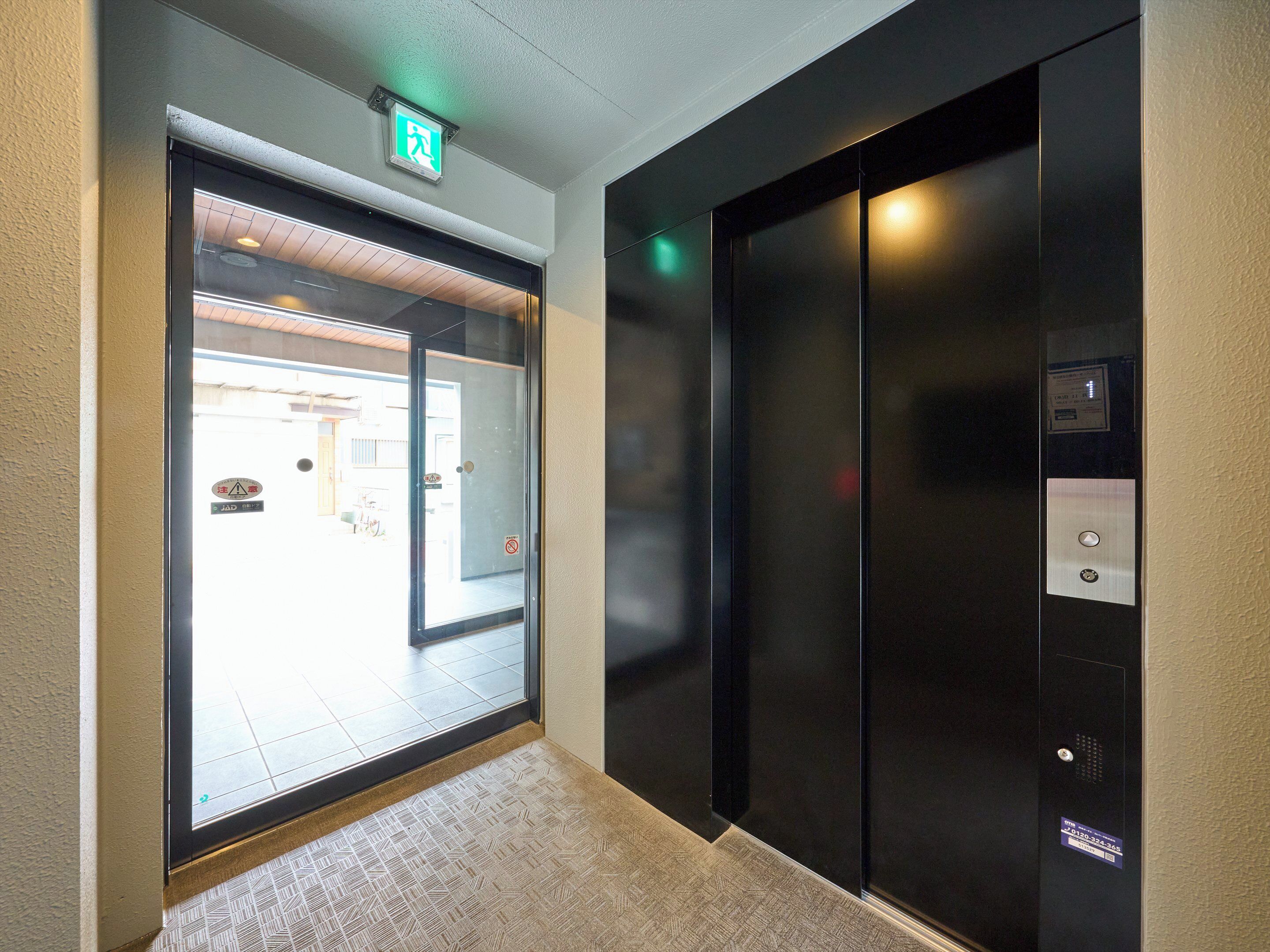 An elevator with a control panel and a glass door entrance.