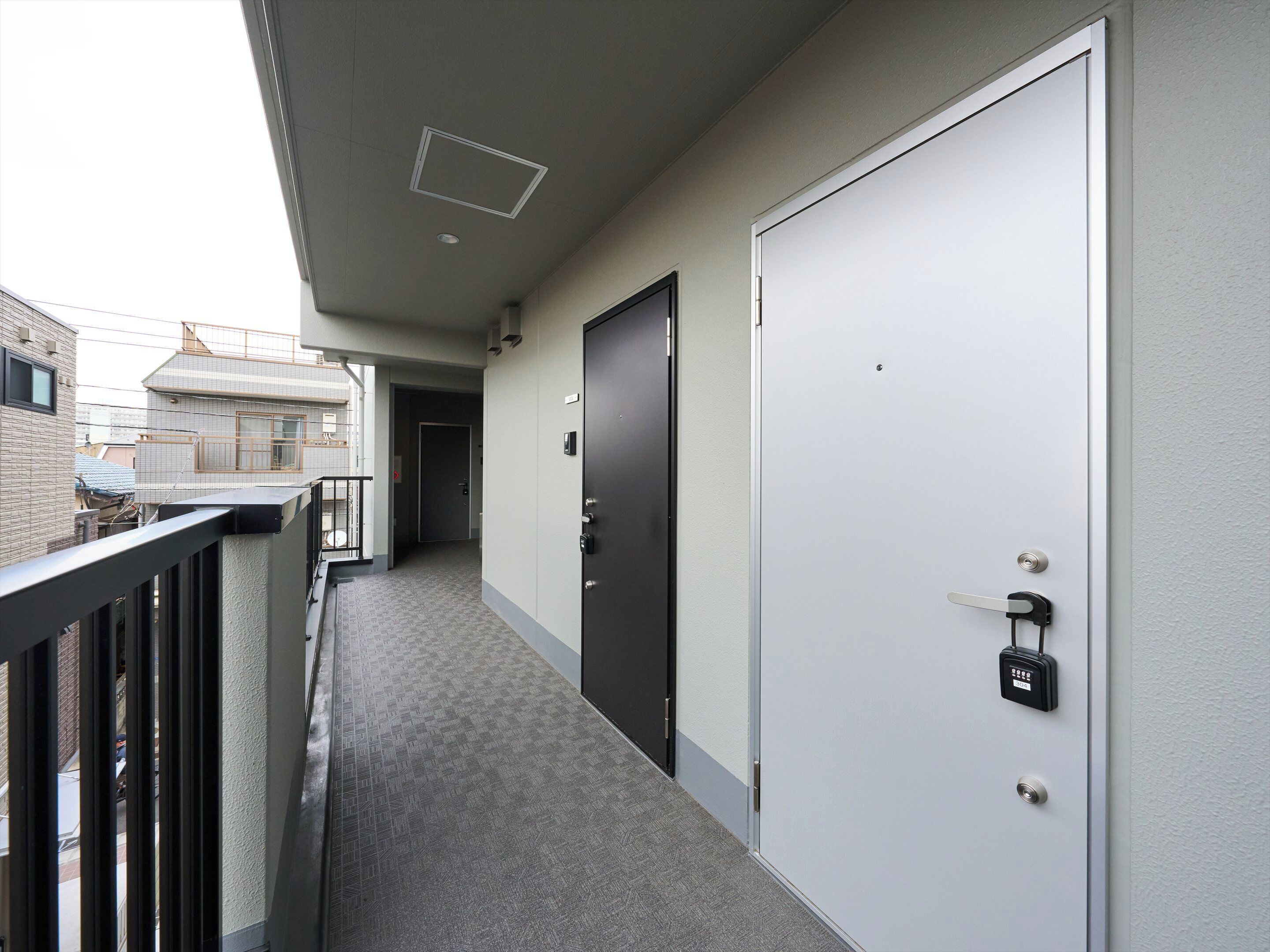 A corridor with a grey carpet, a black door with a lock, and a white door with a keyhole.