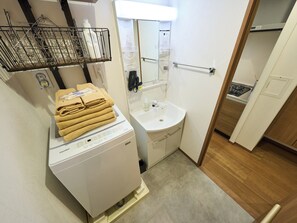 A compact bathroom with a washing machine, a sink, and a mirror. - K-Stay TOKYO HANEDA (Tokyo)