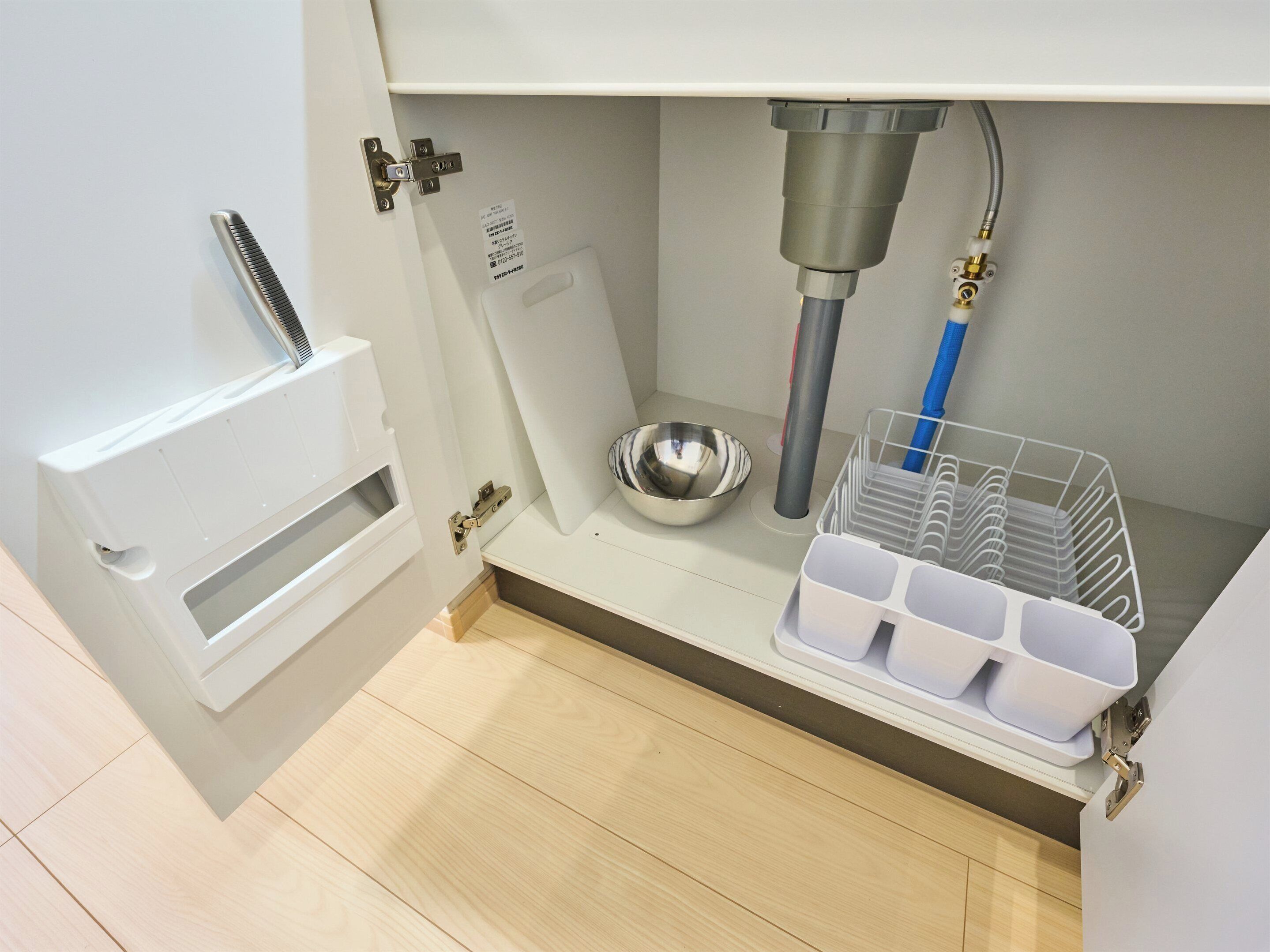 A compact kitchen with a built-in sink, a stainless steel bowl, and a storage rack with containers.