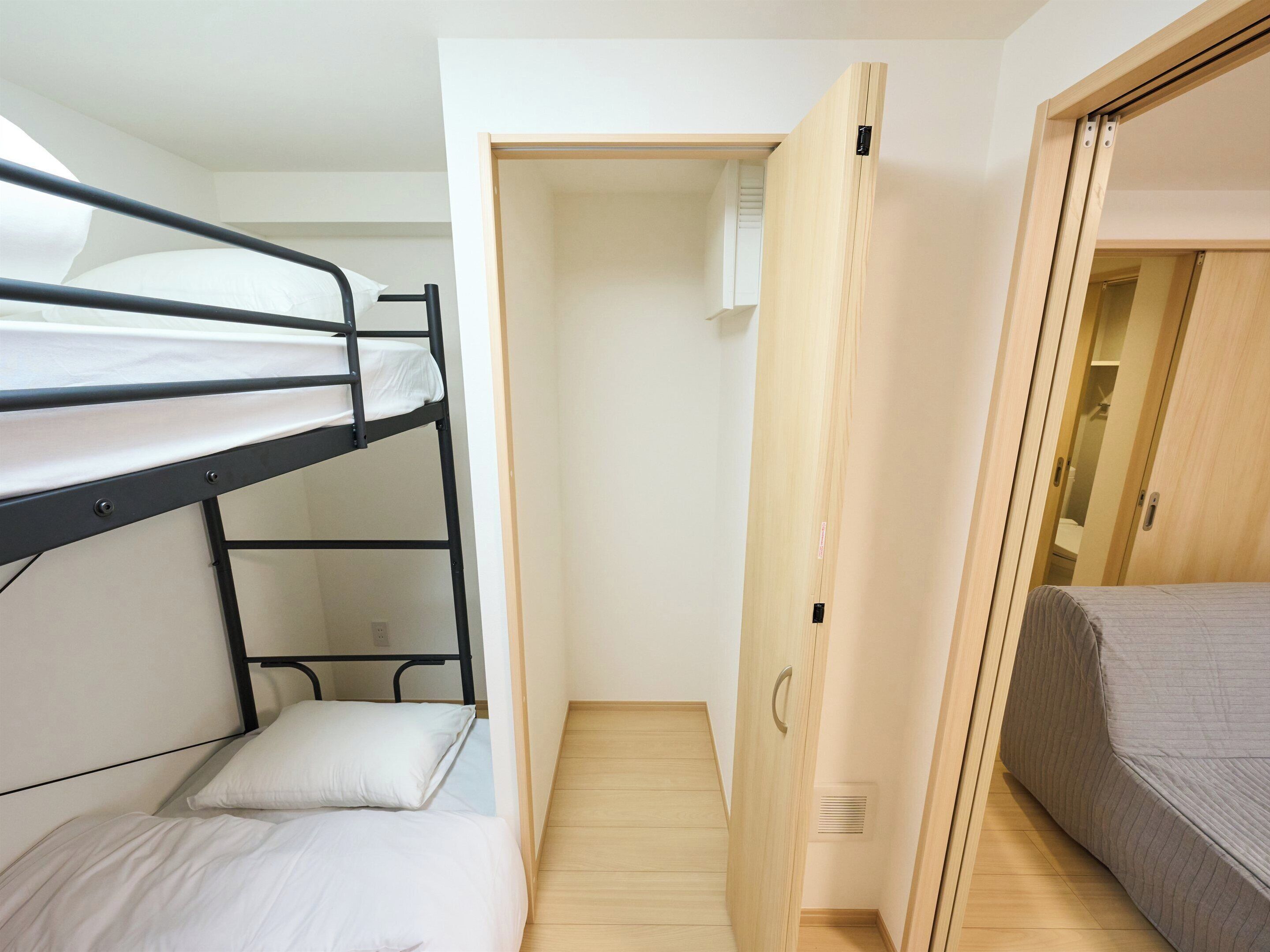 Ein Stockbett mit einem Einzelbett daneben, ein Holzschrank und eine Tür zu einem Schrank.