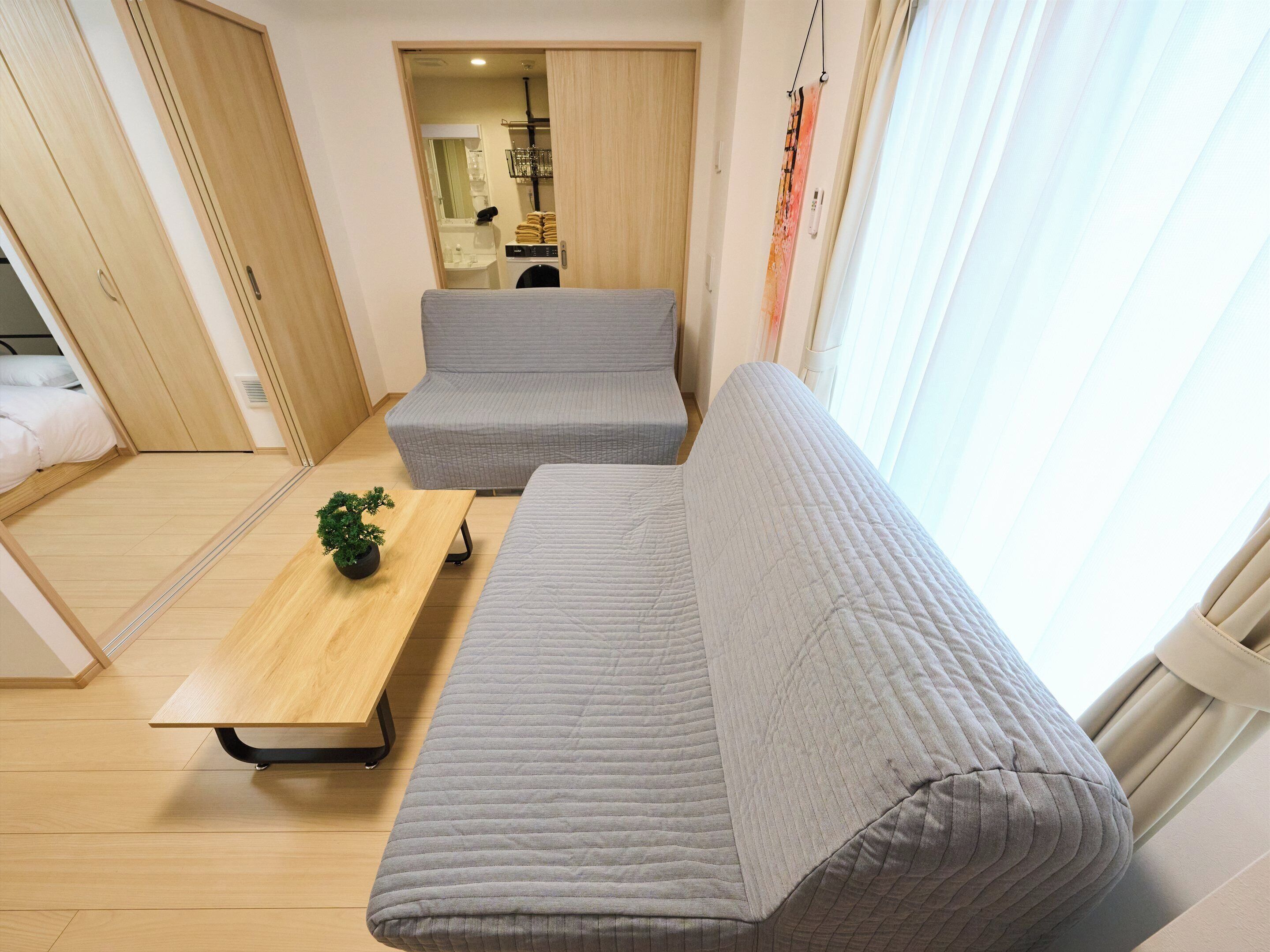 A compact living space with a sofa, a small table, and a potted plant.