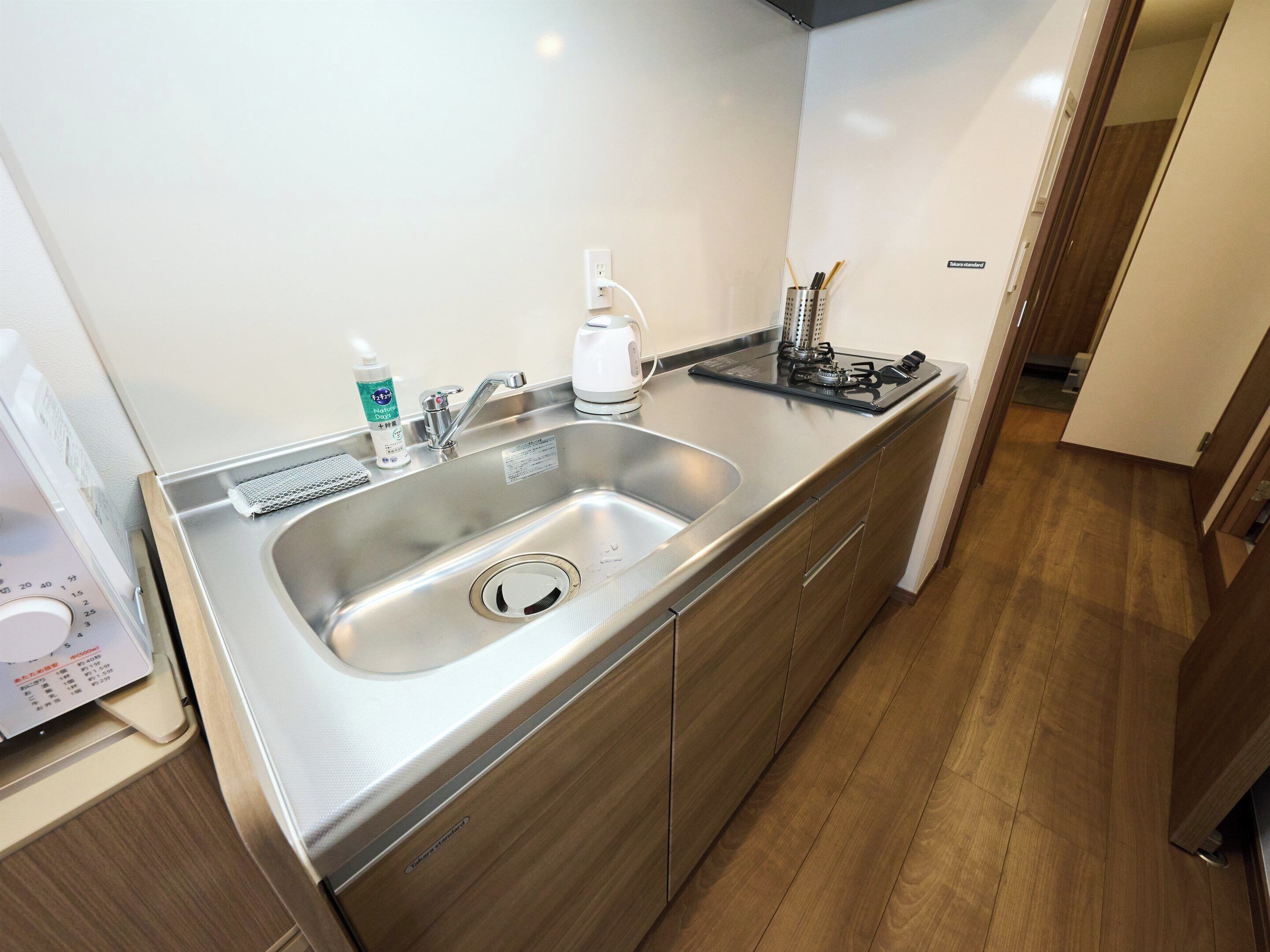 A modern kitchen with a stainless steel sink, a coffee maker, and a gas stove.