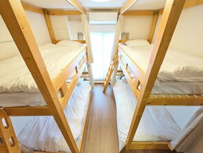 A bunk bed room with wooden frames, white bedding, and a window with curtains. - K-Stay TOKYO HANEDA (Tokyo)