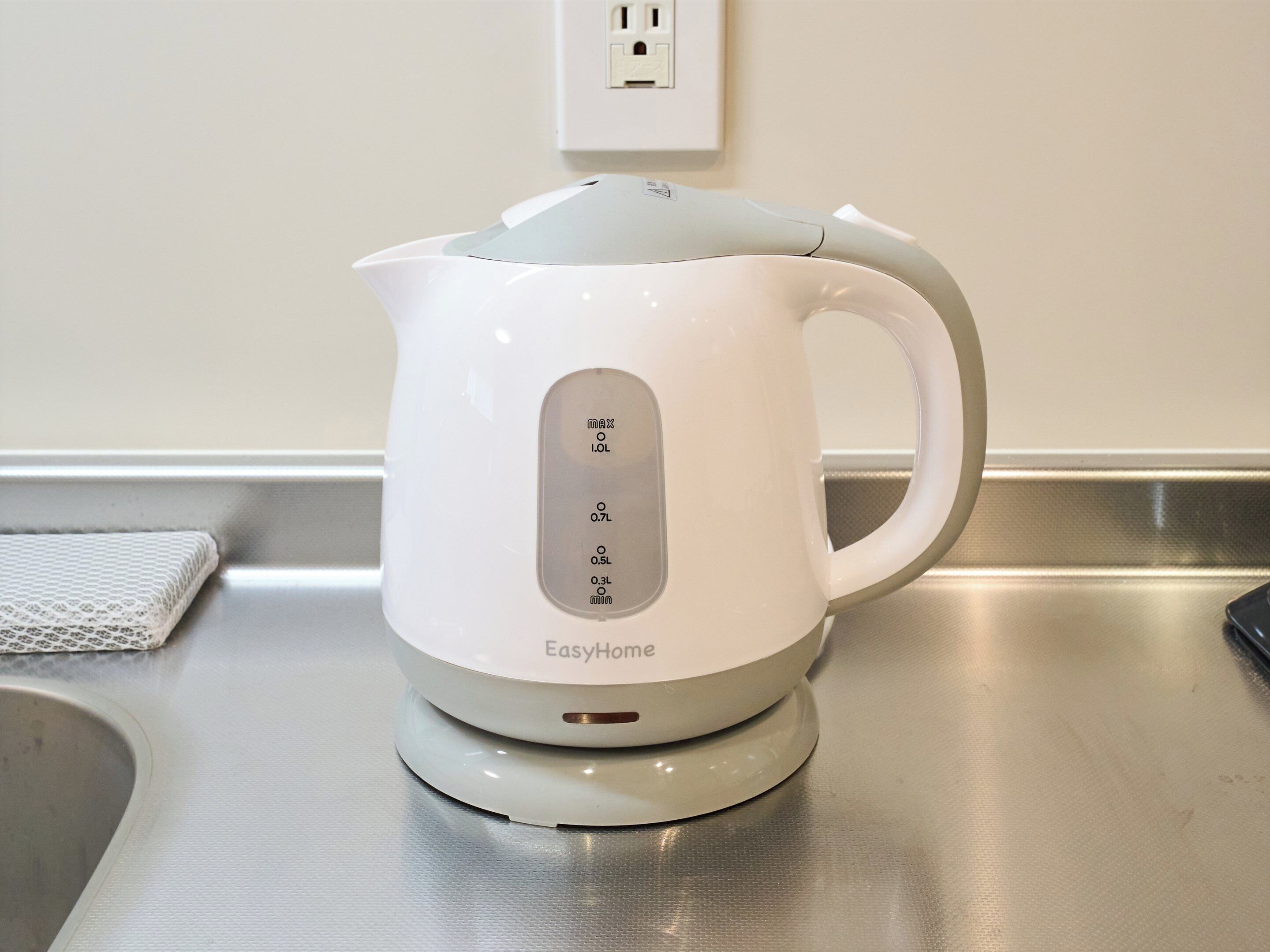 A white EasyHome kettle on a kitchen counter with a power outlet in the background.